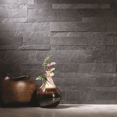 two vases sitting next to each other with flowers in them on a table near a wall