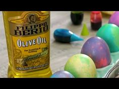 a bottle of olive oil sitting next to some colored eggs