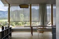 a dining room table and chairs in front of large windows with mountains outside the window