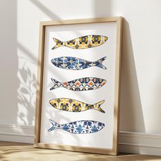 three fish are shown in different colors on a white wall next to a wooden frame