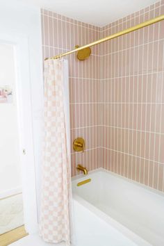 a bathroom with pink tiles and gold fixtures on the shower curtain, tub, and toilet