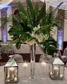 a centerpiece with candles, flowers and greenery is displayed on a round table