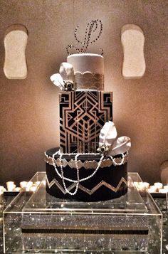 a three tiered black and white cake sitting on top of a glass table next to candles