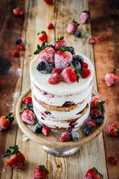 a layered cake with berries and powdered sugar on top is sitting on a wooden table