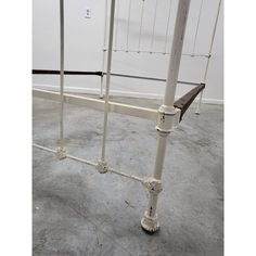 a white metal bed frame sitting on top of a cement floor next to a wall