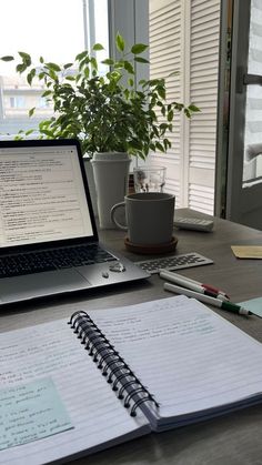 an open laptop computer sitting on top of a desk next to a cup and pen