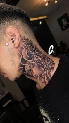 a man with a dragon tattoo on his neck and behind his ear, looking down at the ground