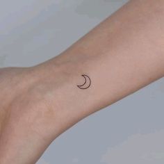 a woman's arm with a small crescent tattoo on it