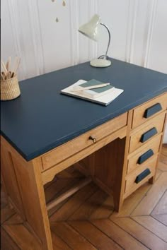 a wooden desk with drawers and a lamp on top