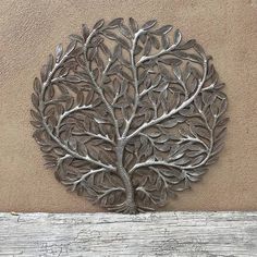 a metal tree is mounted on the side of a wooden wall in front of a building