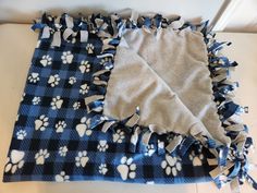 a dog paw print blanket laying on top of a table next to a blue and white towel