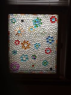 the window is made out of plastic bottles and has flowers painted on it in different colors