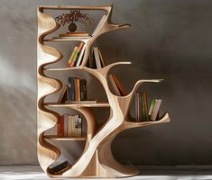 a wooden book shelf with many books on it and a vase in the corner next to it