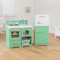 a green play kitchen set with a sink and washing machine in front of the stove