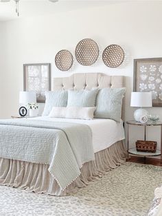 a bedroom with white bedding and blue accents on the walls, along with three round mirrors above the bed