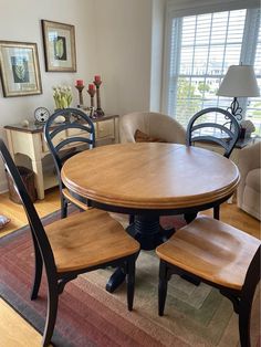 a dining room table with four chairs and a rug on the floor in front of it