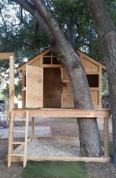 a tree house built into the side of a tree in front of a large tree