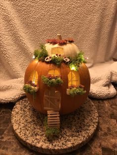 a pumpkin shaped like a house on top of a stone slab with lights in the windows