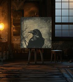 a black bird sitting on top of a painting next to two stools in front of a window