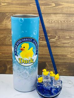 the duck ice bucket is next to two cups with rubber ducks on them, and one cup has blue straws in it