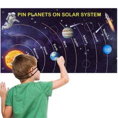 a young boy pointing at the planets on solar system