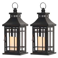 two black lanterns with white candles on them, one is open and the other is closed