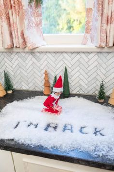 an elf sitting on top of a pile of snow in the middle of a kitchen