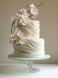 there is a white cake with flowers on the top and bottom tier, sitting on a glass plate