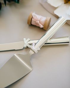 two silver utensils are laying next to each other on a table with flowers in the background