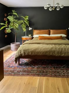 a large bed sitting on top of a wooden floor next to a potted plant