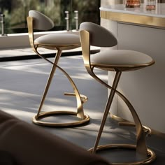 two modern stools sit on the floor in front of an open window, next to a bar