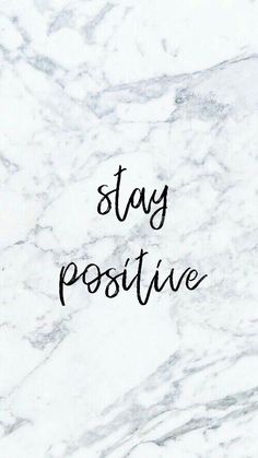 the words stay positive written in black ink on a white marble background