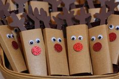 some brown paper bags with reindeer faces on them and red noses are lined up in a basket