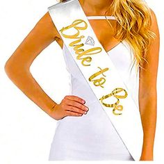 a woman wearing a white dress and gold lettering on her sash is posing for the camera