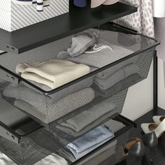 an open drawer with clothes and shoes on it in front of a wall mounted coat rack