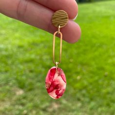 a person is holding out their hand with some earrings on it and grass in the background