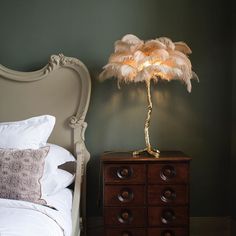 a lamp that is on top of a dresser next to a bed with white sheets and pillows