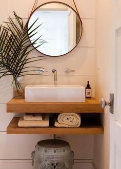 a bathroom with a sink, mirror and potted palm tree in the corner next to it