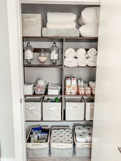 an organized bathroom closet with lots of white towels and toiletries in baskets on the shelves