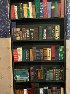 a book shelf filled with lots of books on top of a carpeted floor next to a wall