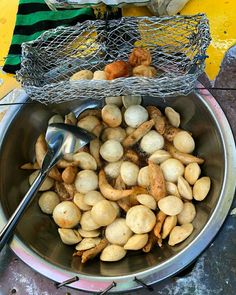 a metal bowl filled with lots of nuts next to a wire basket on top of a table