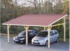 two cars are parked under a carport in a parking lot next to some trees