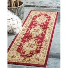 a red and beige rug sitting on top of a floor next to a basket filled with flowers