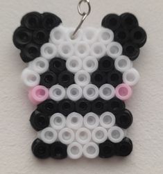 a black and white panda bear with pink eyes is hanging from a silver metal hook