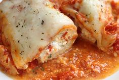 two stuffed shells covered in sauce and cheese on top of a white plate with parmesan