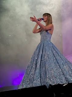 a woman in a blue dress singing into a microphone