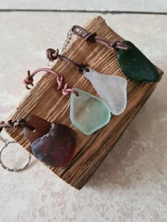 four sea glass pieces are sitting on a piece of wood with a keychain