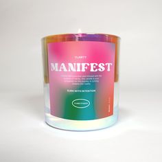 a candle that is sitting on top of a white surface with the words mainfest printed on it