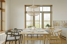 a dining room table and chairs in front of large windows