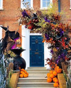 halloween decorations on the steps in front of a house with blue door and pumpkins